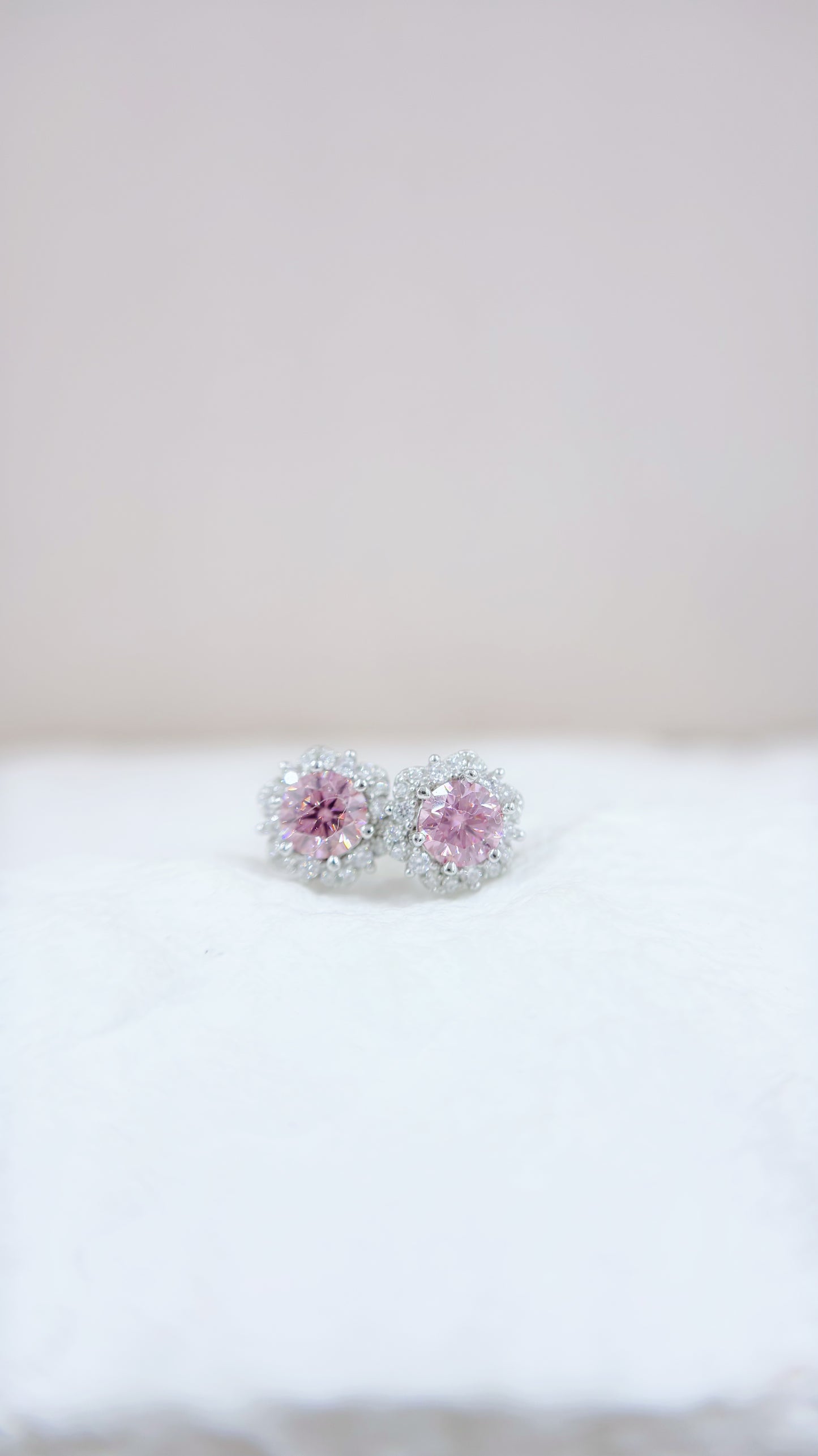 Pair of earrings with pink gemstones on a white surface