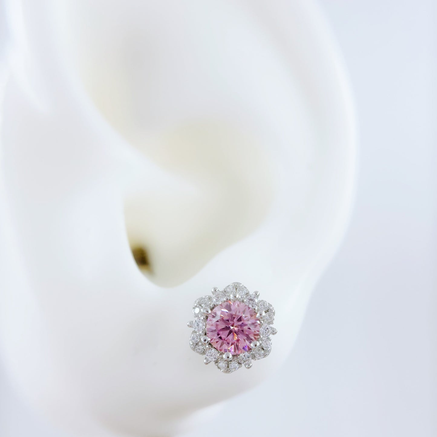 Pink flower-shaped earring on a white background