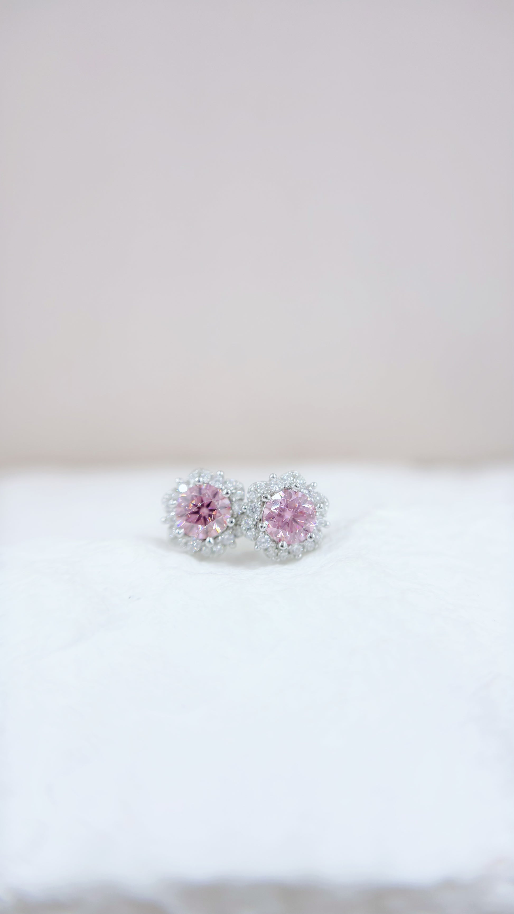 Pair of earrings with pink gemstones on a white surface