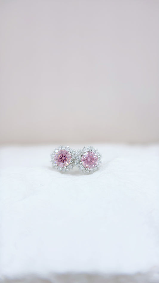 Pair of earrings with pink gemstones on a white surface