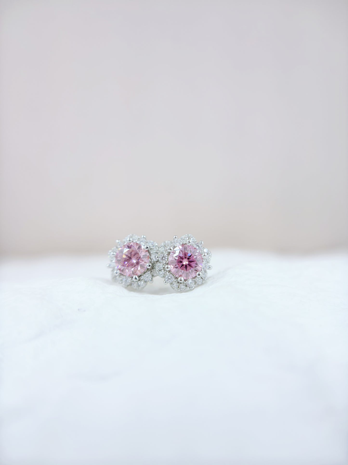 Pair of pink gemstone earrings on a white surface with a light gray background