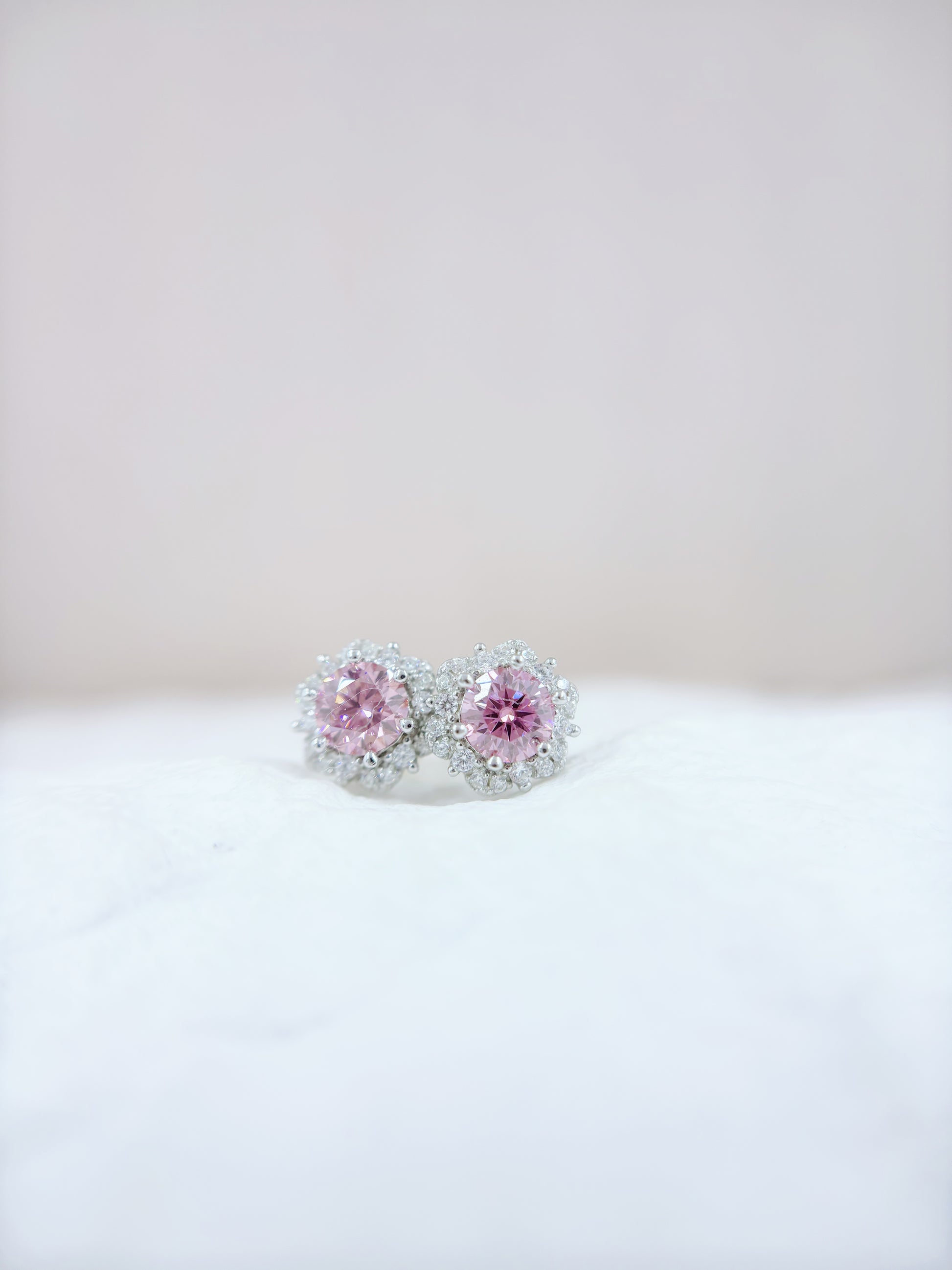 Pair of pink gemstone earrings on a white surface with a light gray background